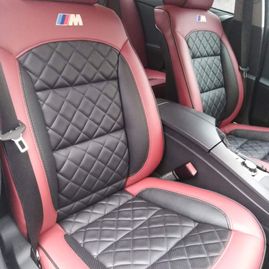 Forsetene på en bil som er røde med sorte detaljer i midten av setene med kryvsmønster