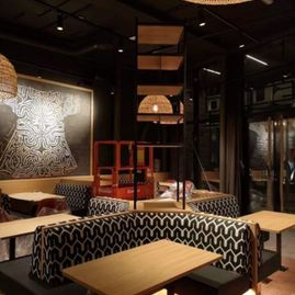 Interiøret i en restaurant med sorte vegger, retro møvler og spotlys i et sort tak samt hengende lamper med lampeskjermer av strå